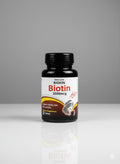 Bottle of Biotin supplement with label on a gray background