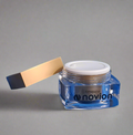 Blue jar of novion product with a applicator on a gray background